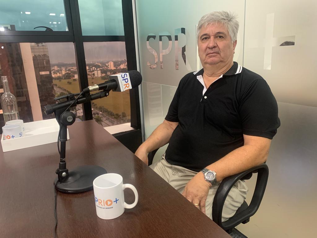 Sidiney Peruchi de Godoy, presidente da ACI SJC (São José dos Campos), com camiseta preta, relógio, calça clara, sentado em uma cadeira preta com uma mesa de madeira em sua frente; foto ilustra matéria sobre revitalização do centro.