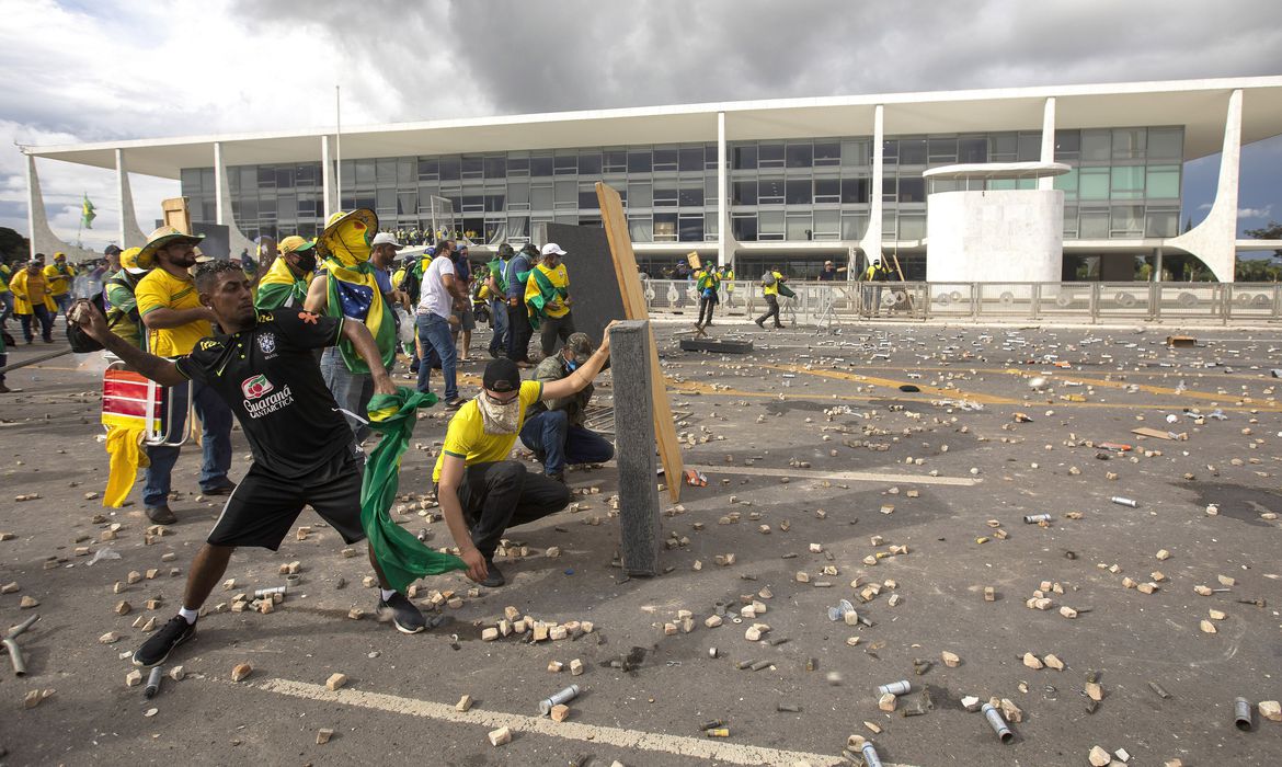 Terroristas com a camisa do Brasil atacando pedras na Praça dos Três Poderes, em Brasília; foto ilustra matéria sobre STF ter tornado réus 200 acusados.
