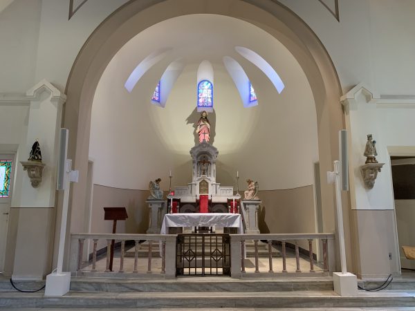 Altar da Capela do Vicentina Aranha, localizada dentro do parque, na região central de São José dos Campos; foto mostra uma imagem ao fundo, mesas e cadeiras, parede marrom e iluminação baixa vindo do teto.