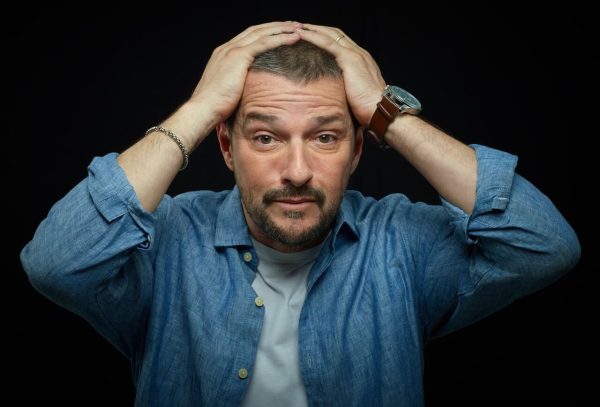 marcelo serrado em fundo preto colocando as mãos sobre a cabeça e expressão de desespero