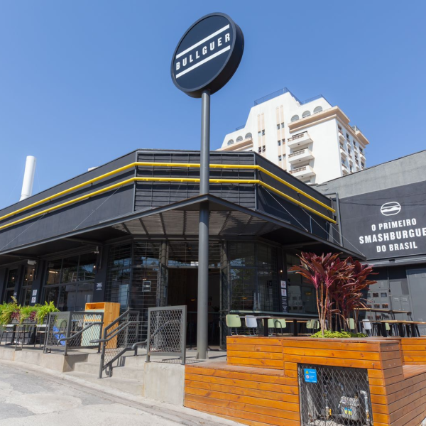 Fachada do Bullguer, no Jardim Aquarius, com um céu azul ao fundo e construção em preto, amarelo e detalhes em madeira; foto ilustra matéria sobre hamburguer artesanal em SJC.