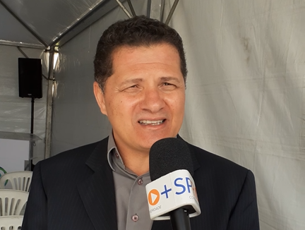 Izaias Sanatana, prefeito de Jacareí pelo PSDB, durante entrevista sobre aumento (reajuste) dos salários dos servidores públicos da cidade; na foto ele veste um terno preto e uma camisa cinza, enquanto fala em um microfone.