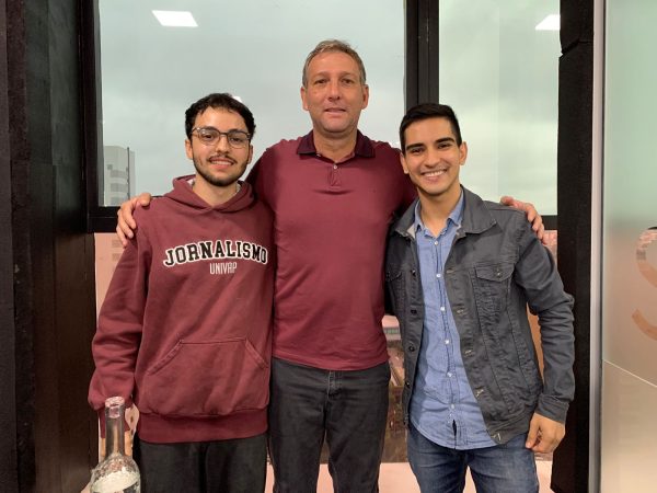 Matheus Andrade (jornalista), Rodrigo Almeida (jornalista) e Ricardo Costa (técnico do São José EC), em frente a um vidro, com São José dos Campos ao fundo, após entrevista.