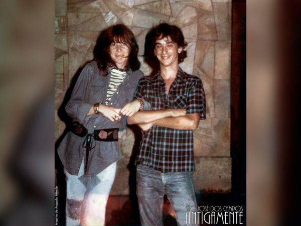 Rita Lee em São José dos Campos, ao lado de um homem, em frente a uma parede, druante um show na Associação Esportiva São José, na década de 1970.
