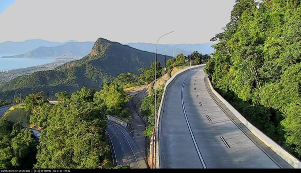 Trecho da Rodovia dos Tamoios, sentido São José dos Campos (Serra Nova), com área verde pelas laterais, montanhas ao fundo e estradas do centro.