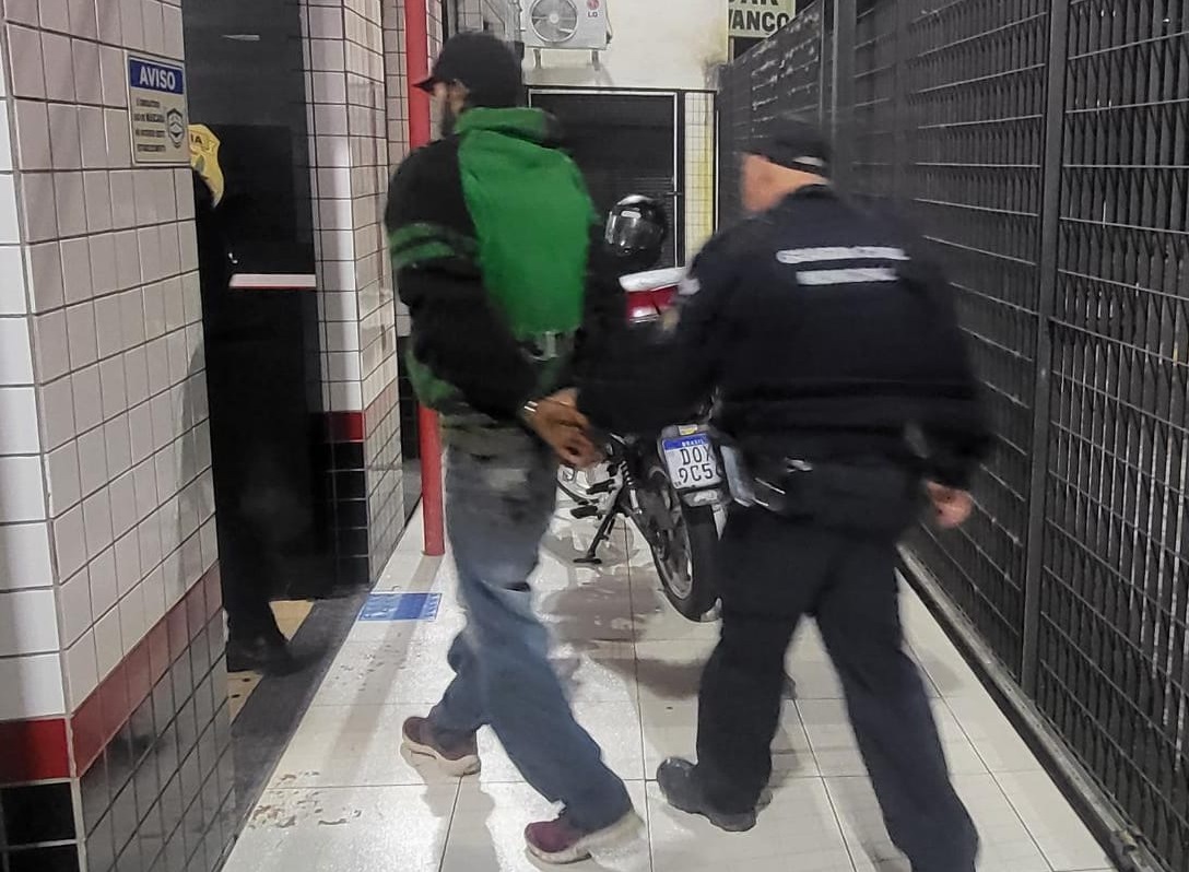 homem sendo preso por guarda civil. Câmeras de escola em Taubaté auxiliaram na prisão dos responsáveis pelo furto da fiação
