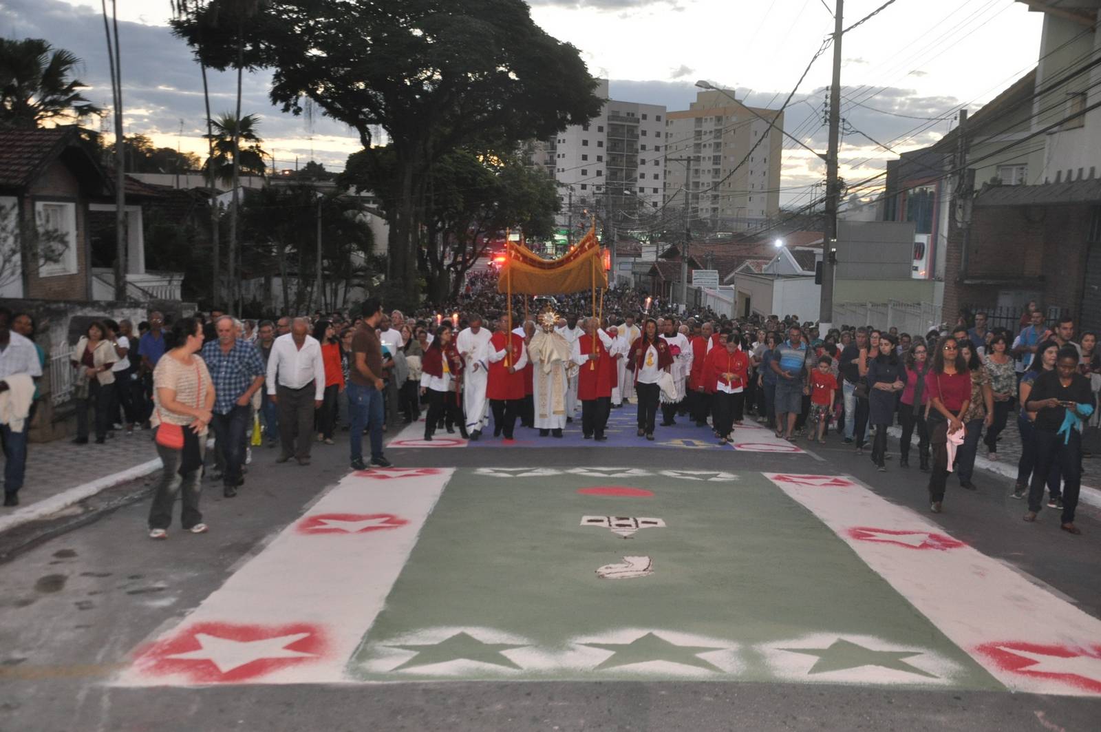 Fiéis caminhando por rua sob tapete de Corpus Christi em Caçapava; trânsito será alterado para passagem de cortejo