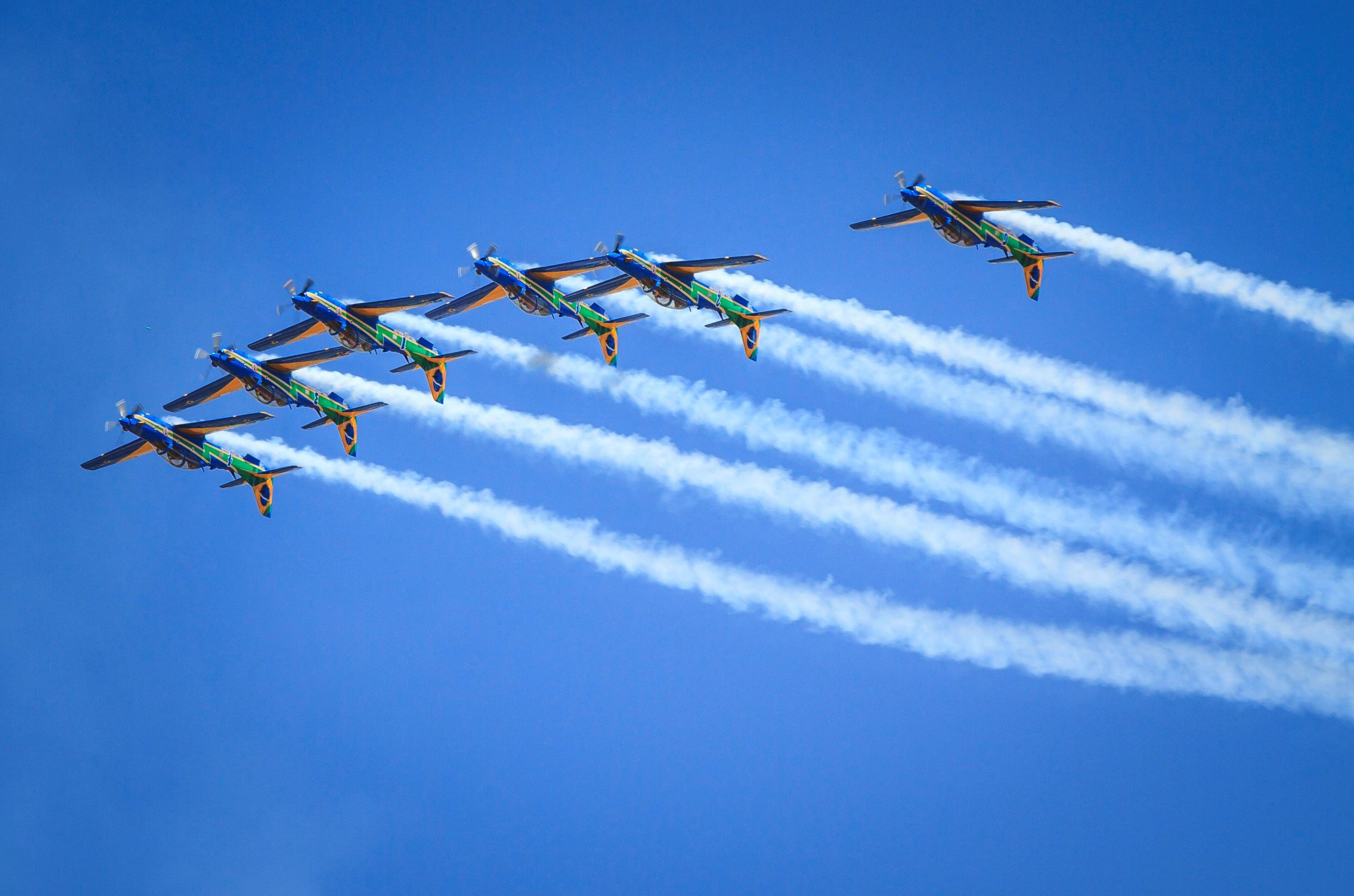 Esquadrilha da Fumaça fazendo manobra em grupo, colocando os aviões de cabeça para baixo enquanto estão agrupados em linha. A Embraer e a Força Aérea estão anunciando atualizações para a frota responsável pelas atividades da Esquadrilha da Fumaça