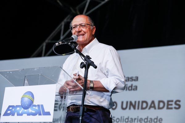 vice-presidente geraldo alckmin discursando em palco com microfone à frente em pedestal