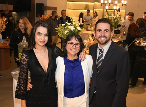 Mulher de vestido preto, senhora de terno branco e blusa azul e homem de terno preto e grata listrada