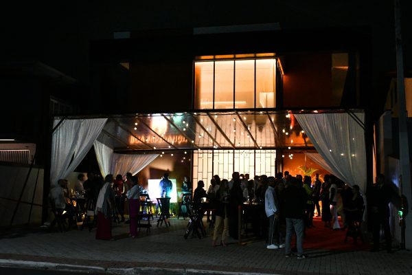 Evento com luzes, cortinas brancas a noite e muitas pessoas se divertindo