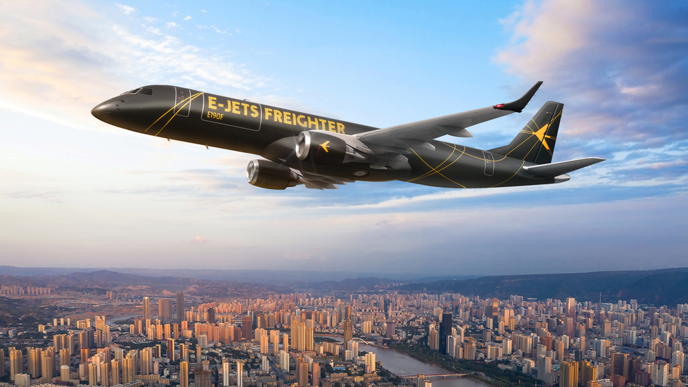 Jato preto da Embraer voando sobre cidade. A embraer lançou novo sistema de manutenção no mesmo dia que firmou acordo de conversão de jatos comerciais para cargueiros com grupo chinês.