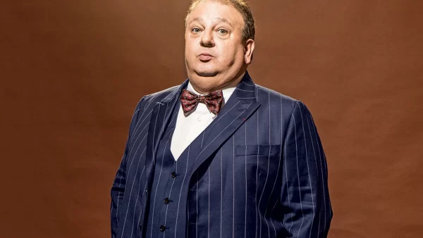 érick jacquin posando de terno para foto com as mãos no bolso da calça e fazendo bico