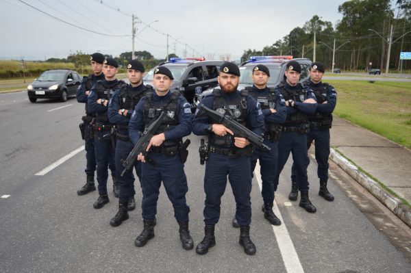 novos agentesda ronda ostensiva municipal de sjc em formação na frente de viaturas suv. eles vestem farda com boina e seguram armamento pesado.
