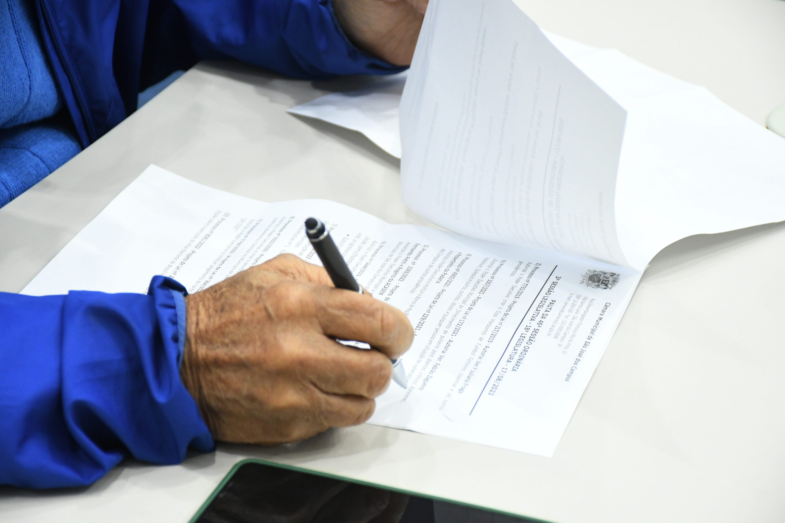 homem com caneta vendo documento de pls para ajudar jovens e empresas