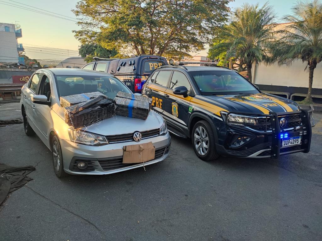 Veículo Voyage com pacotes contendo 90kg de maconha, que foram apreendidas, em cima de capò. Ao lado, carro da Polícia Rodoviária Federal (PRF)