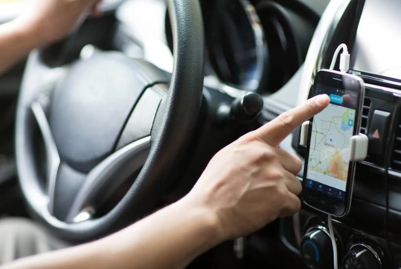 Motorista de aplicativo mexendo em celular em suporte dentro do carro; motorista de aplicativo de Jacareí sofreu golPe do PIX