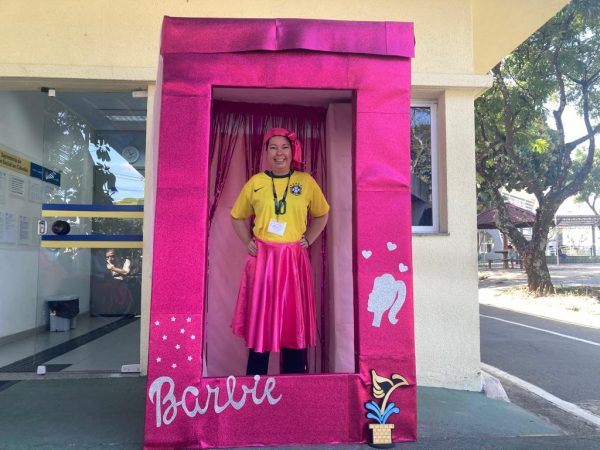 frequentadora do centro da juventude tirando foto na caixa da barbie inclusiva