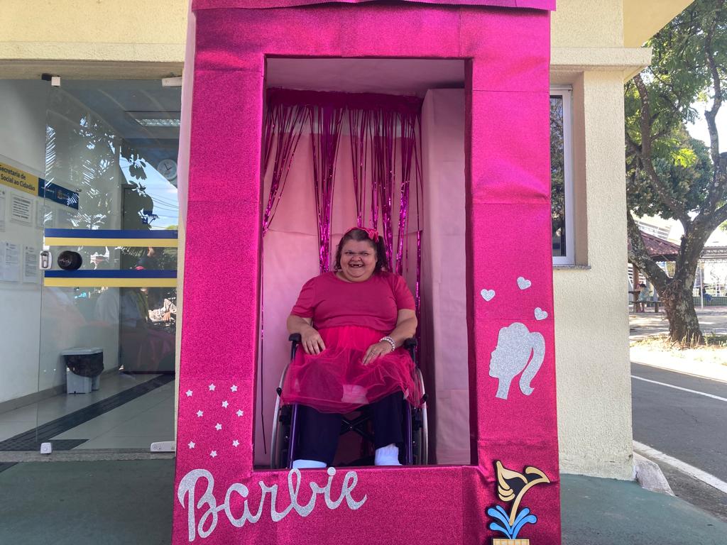 frequentadora do centro da juventude tirando foto na caixa da barbie inclusiva