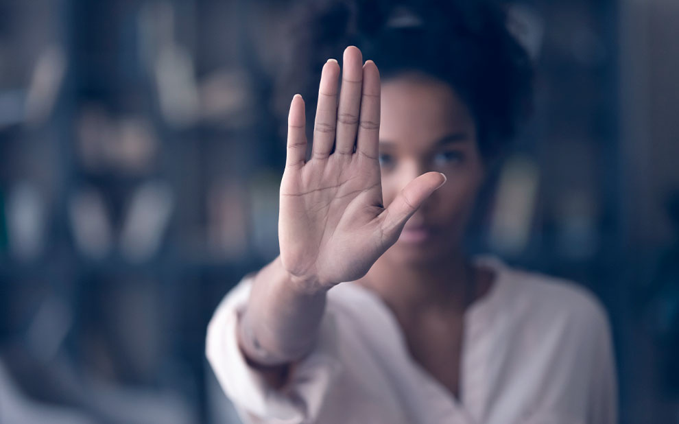 Mulher com a mão estendida para frente em sinal de combate à violência contra mulher