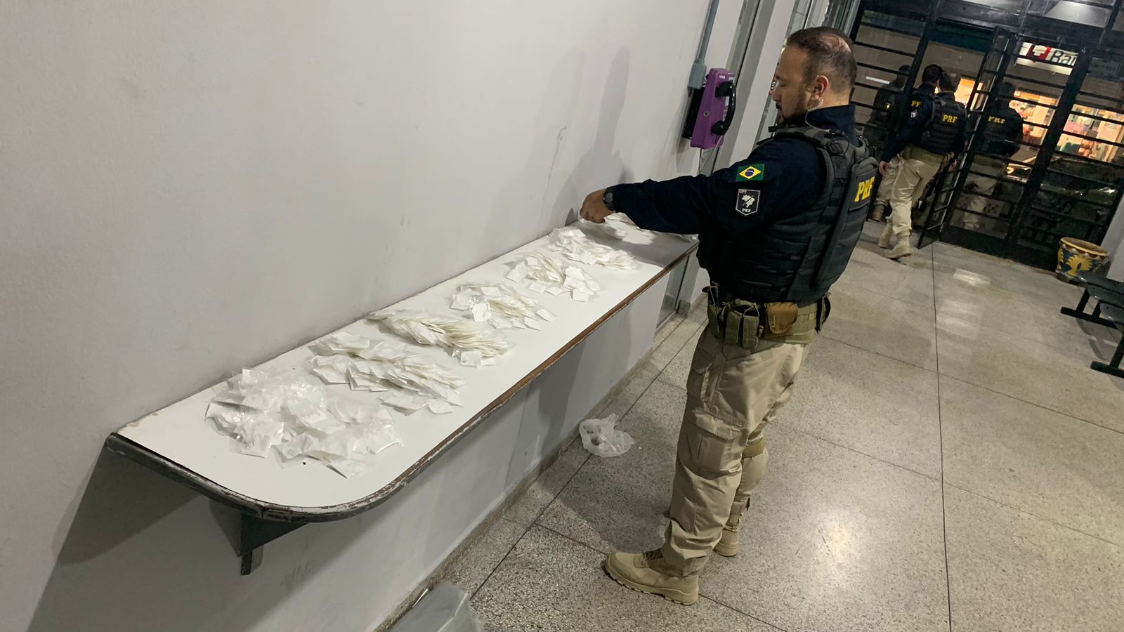 Agente da PRF (Polícia Rodoviária Federal) contando as mil porções de cocaína apreendidas na Dutra em Jacareí