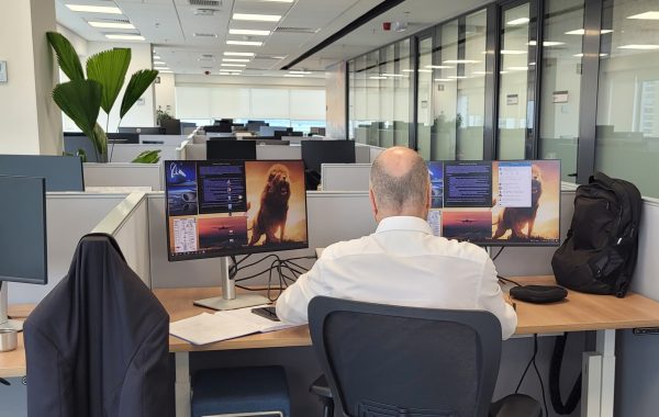 funcionário da boeing sentado de costas em frente a computador no novo escritório em são josé dos campos. ele é calvo e veste camisa social clara.