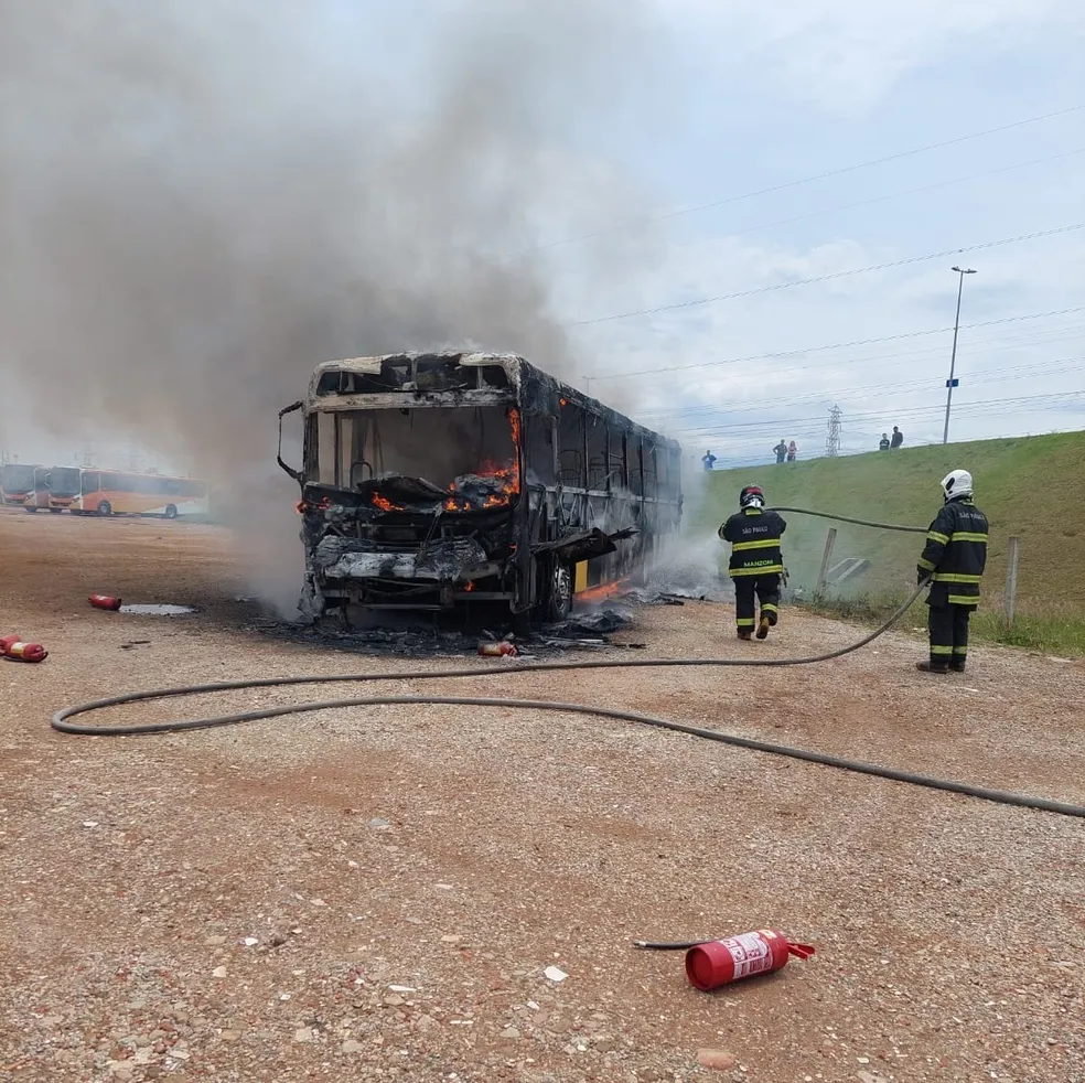 ônibus tendo chamas do incêndio apagadas por bombeiros com mangueiras, em São José