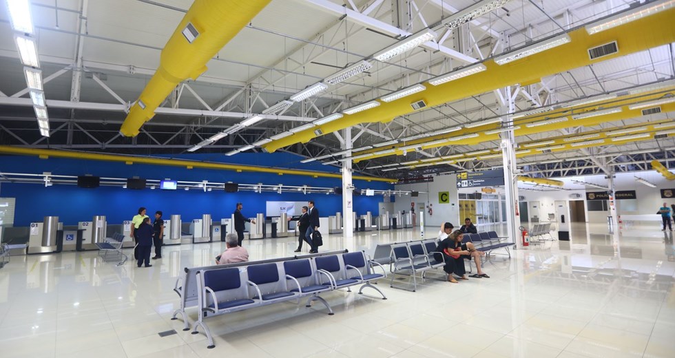 Saguão do Aeroporto de SJC com pessoas sentadas e cadeiras vazias