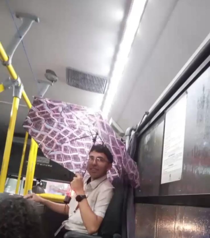 Cobrador com guarda-chuva aberto devido a goteira em ônibus da linha 237 em SJC