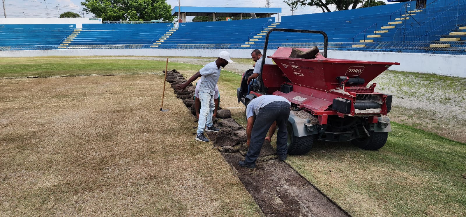profissionais fazendo trabalahos de revitalização no gramado do martins pereira commáquina similar a pequeno trator