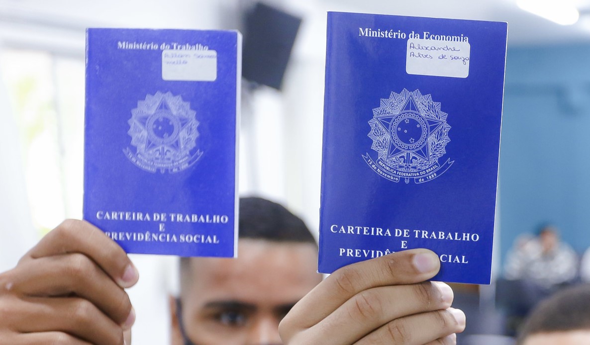 mãos de dois homens segurando carteiras de trabalho levantadas