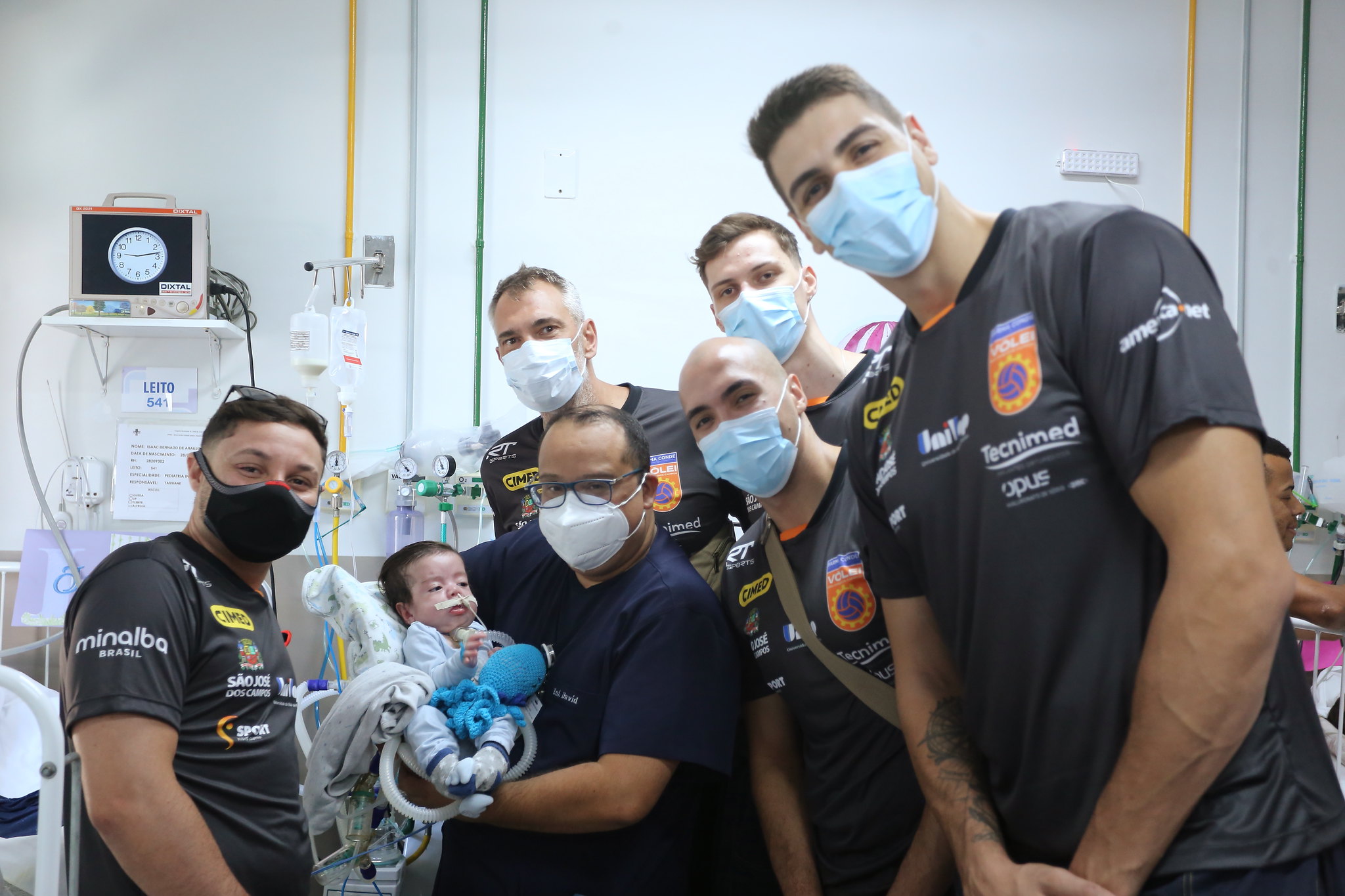 jogadores do vôlei são josé posando de máscara para foto ao lado de profissional da saúde segurando bebê