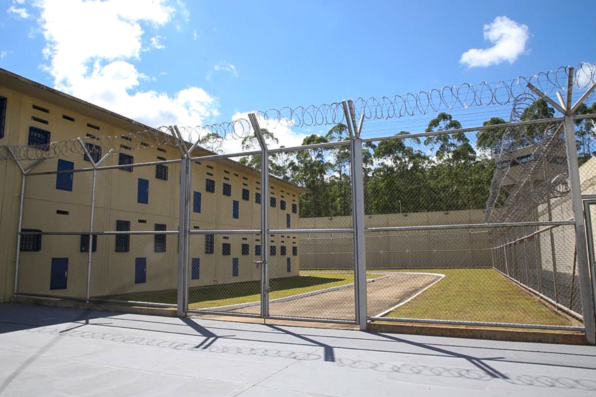 grade de penitenciária ao lado de prédio com várias janelas, onde devem ficar os detentos