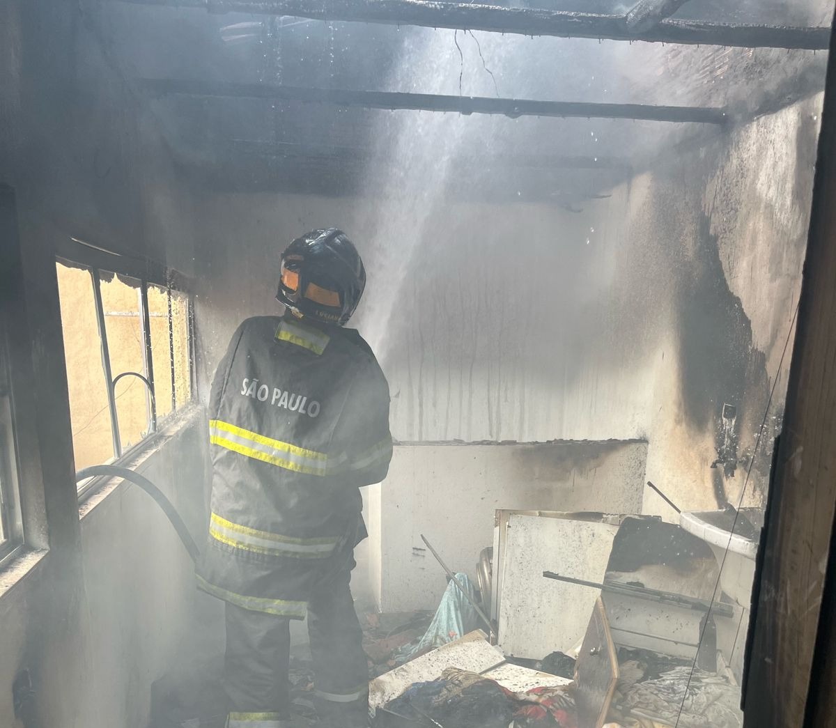 Bombeiro em atendimento a incêndio no cômodo de uma residência em São José