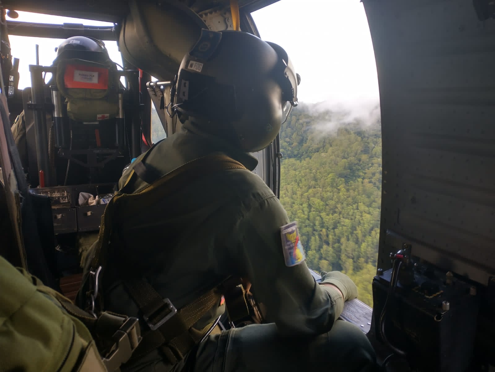 militar da fab olhando paisagem em busca de helicóptero desaparecido dentro de outra aeronave