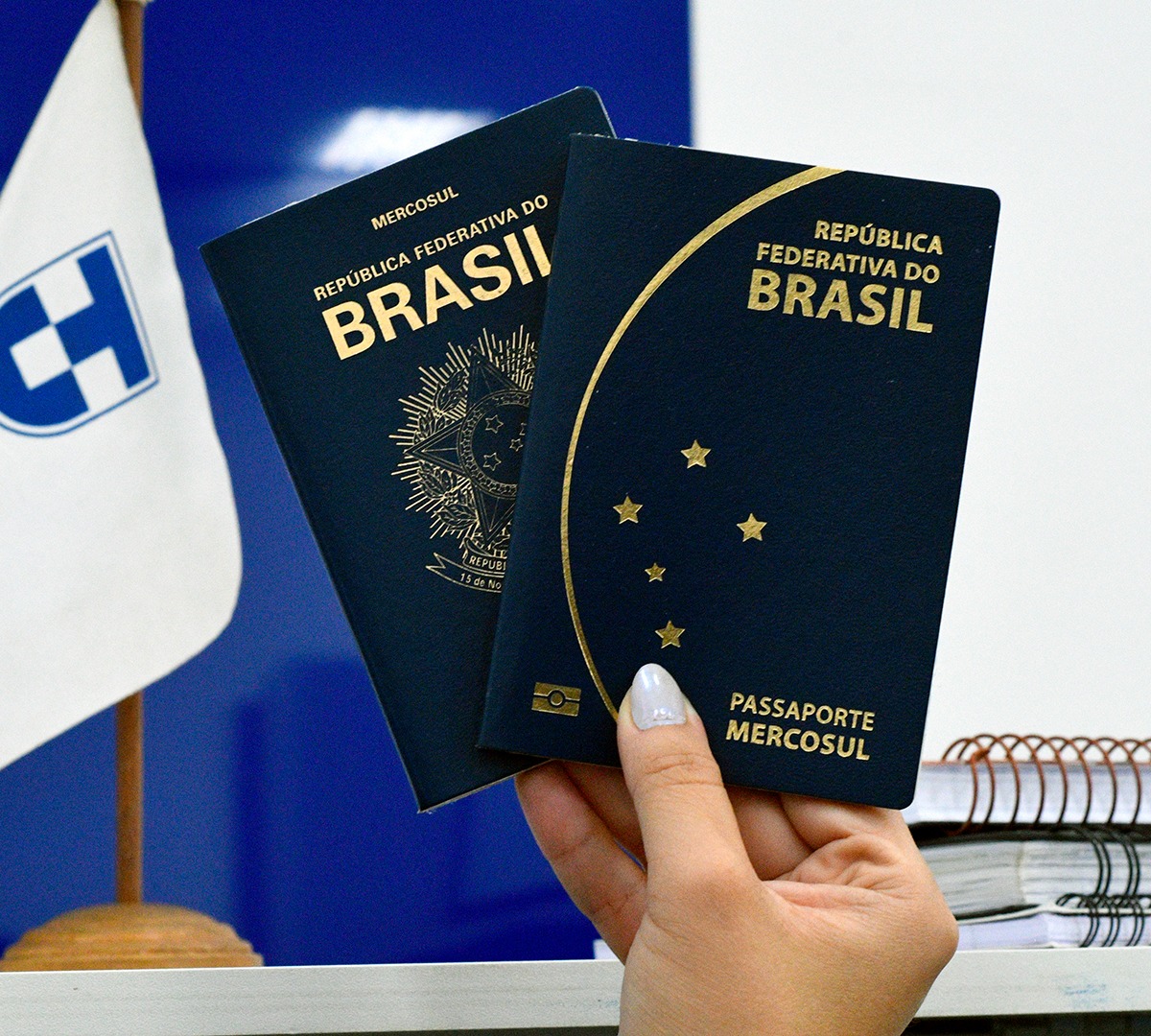 mão de pessoa segurando dois passaportes brasileiros