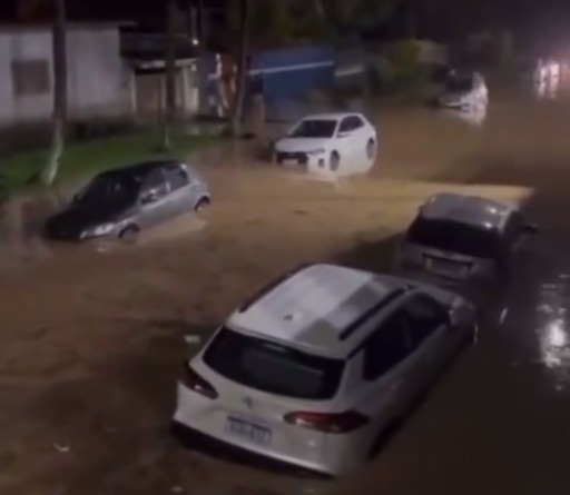 Alagamento de rua na cidade de Caraguatatuba, causado por chuvas que caem no Litoral Norte; carro está submergido em água, na altura das portas