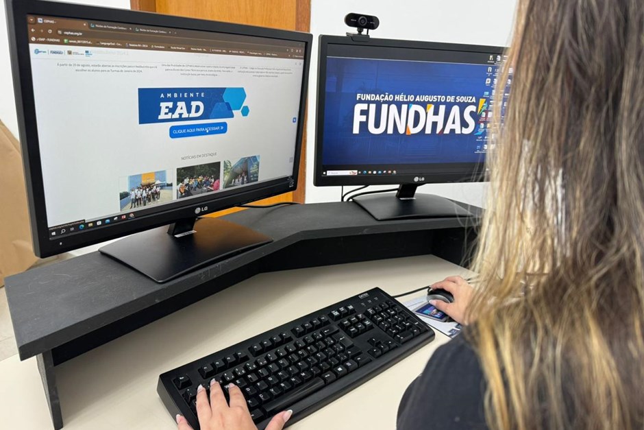 garota navegando no site do cephas visualizando cursos ead em dois monitores distintos