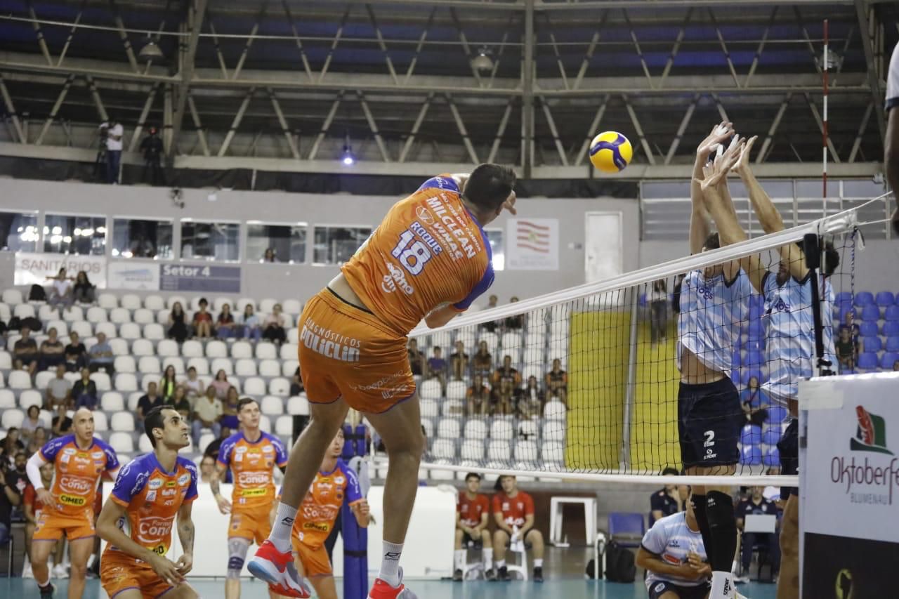 Atleta do Vôlei São José atacando a bola enquanto bloqueio sobe para impedir avanço no Sul-Americano