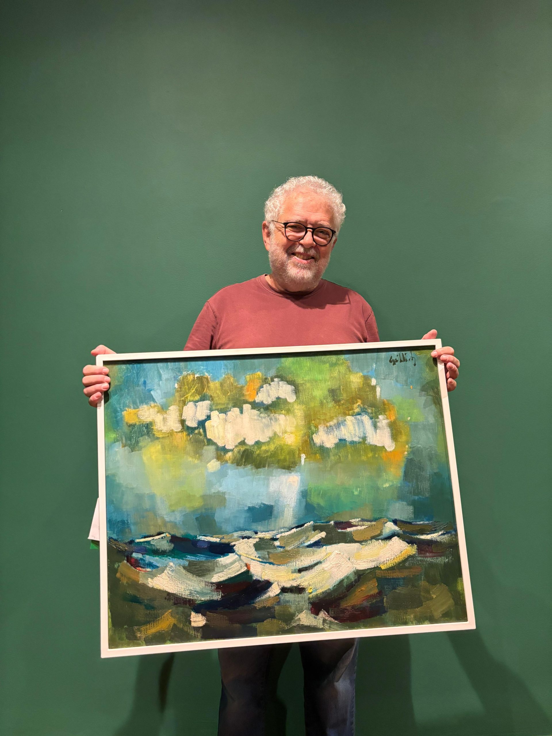 fabio sapede segurando um dos quadros da sala trópicos da exposição de gutlich