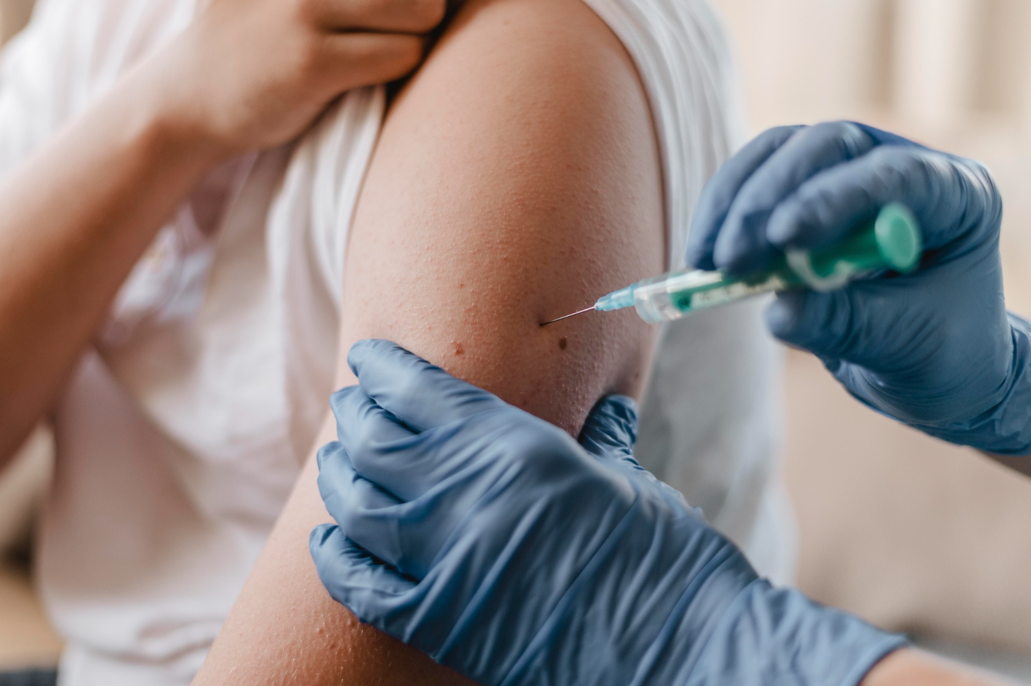 profissional da saúde aplicando vacina em adolescente copm luva azul