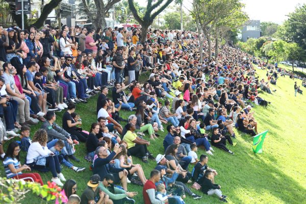 população sentada no morro abaixo da avenid anchieta vendo apresentação da esquadrilha da fumaça