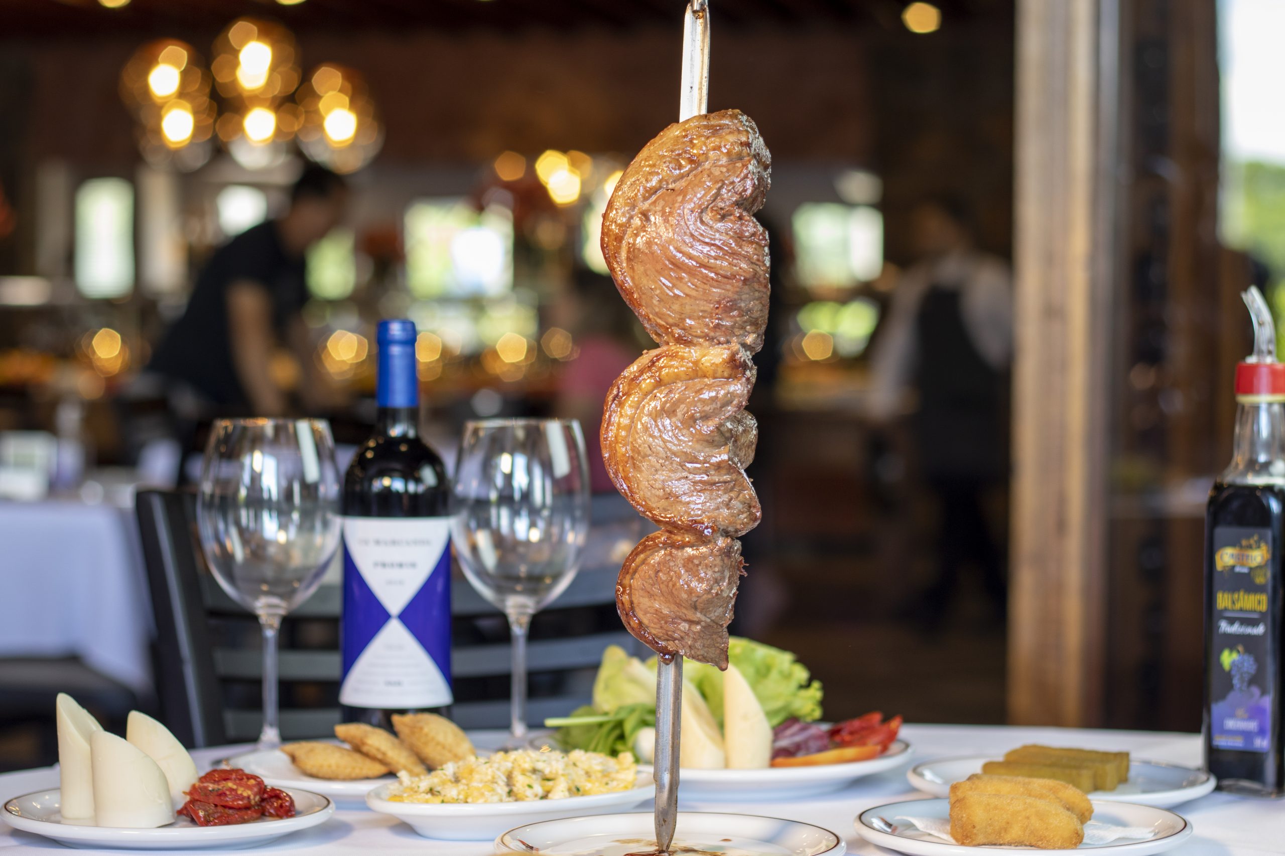 Mesa com carne e vinho na Churrascaria Estância