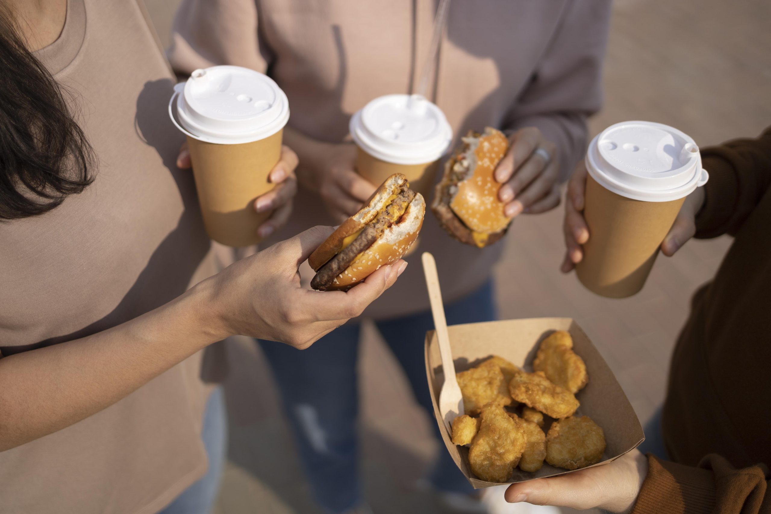 grupo de pessoas segurando copos e hambúrgueres de festival de comida de rua