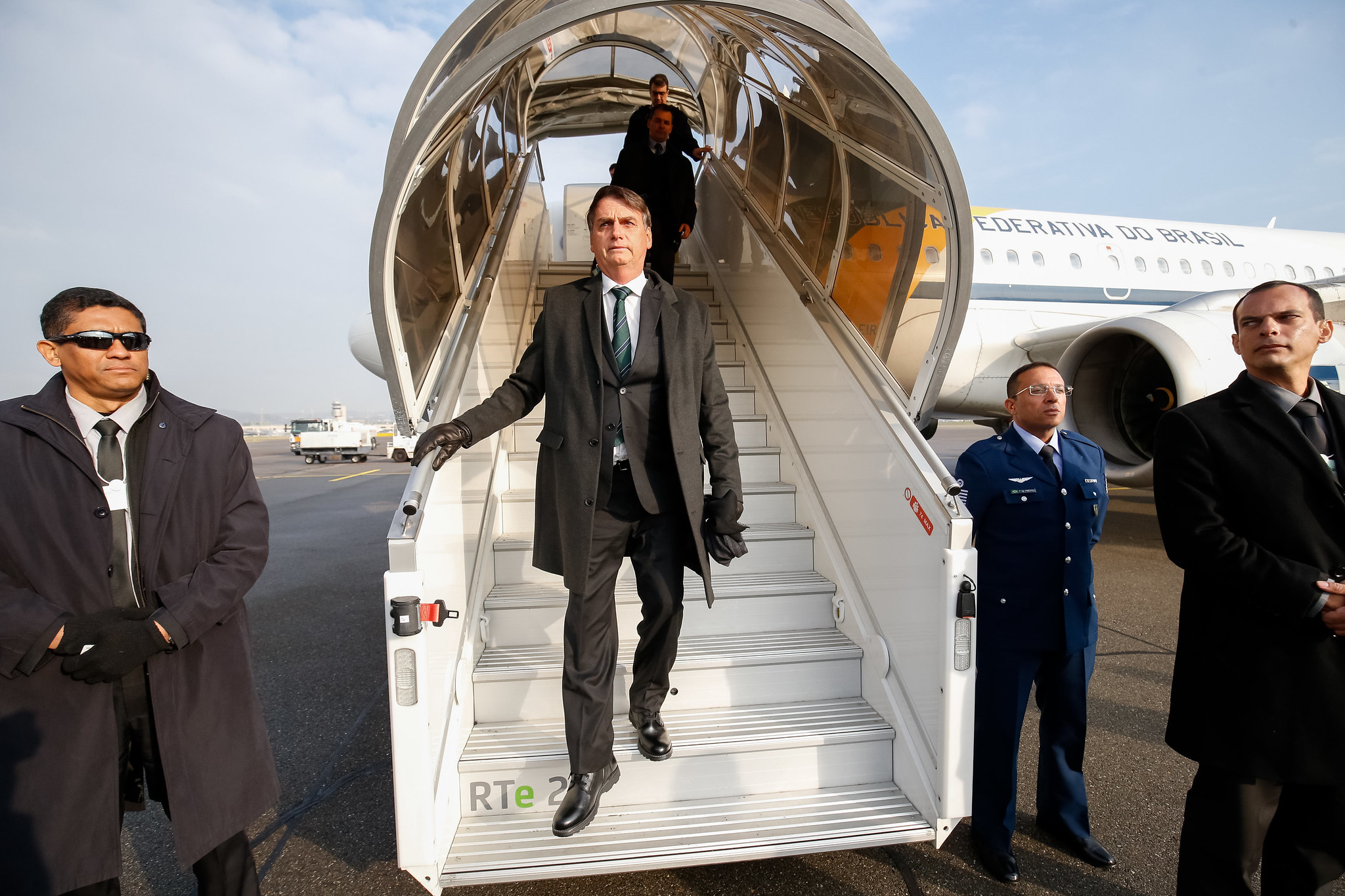 jair bolsonaro descendo de escada de avião acompanhado de comitiva quando era presidente