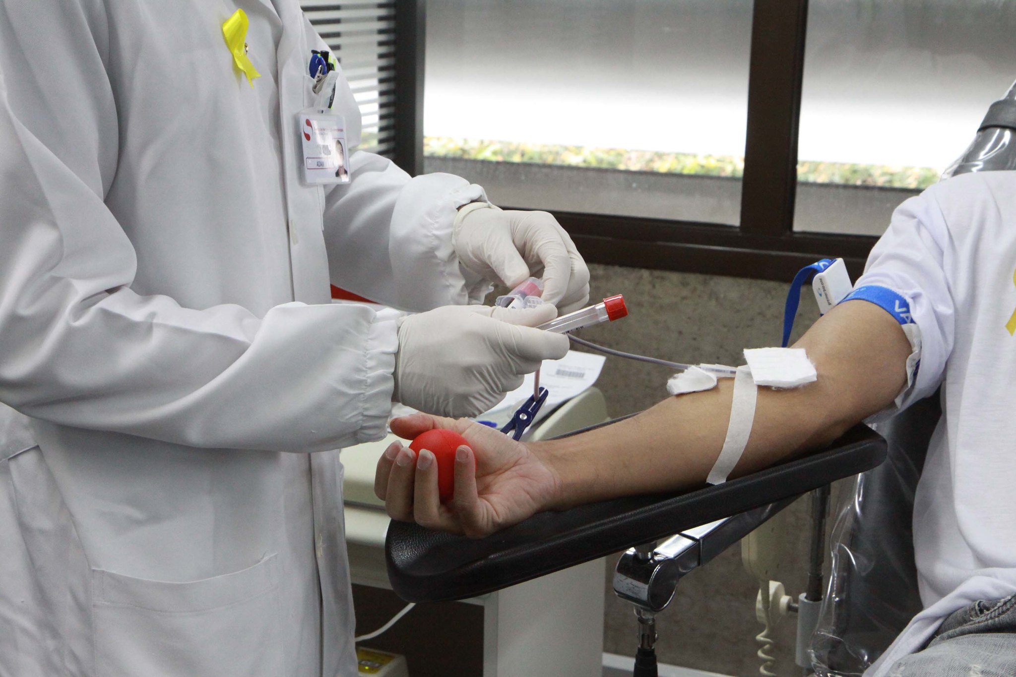 pessoa doando sangue enquanto profissional da saúde faz coleta