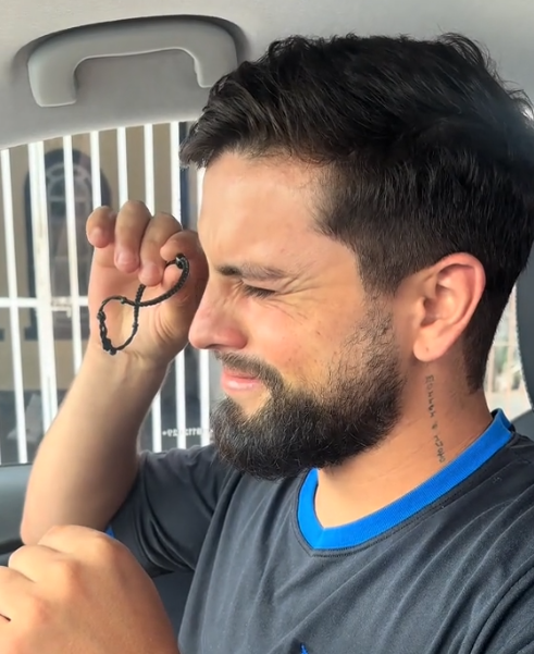 namorado emocionado dentro do carro olhando por dentro de pulsiera com foto da mãe