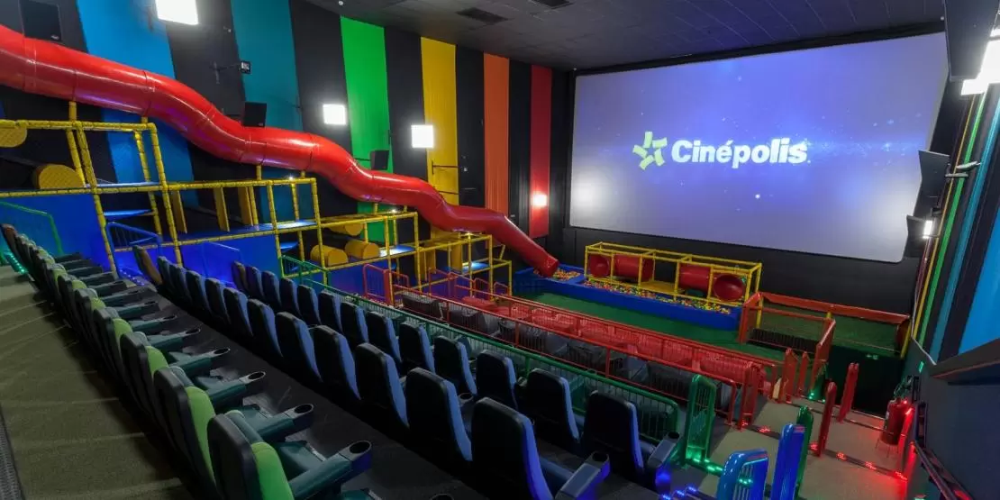 Parte interna de uma das salas do Cinépolis Shopping Jardim Oriente, um dos cinemas em SJC, com salas kids e um tobogã vermelho ao lado esquerdo.