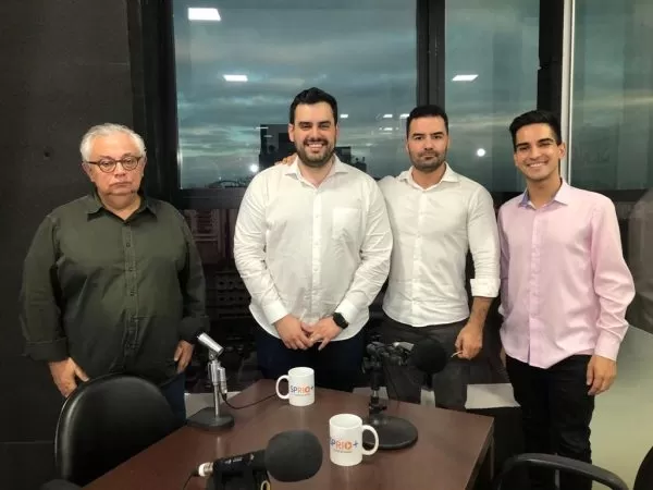 José Guilherme Ferreira (jornalista), Renato Battista (candidato a deputado estadual pelo União Brasil), Arthur do Val (União Brasil) e Matheus Andrade (jornalista)., em frente a uma janela, com a vista de São José dos Campos ao fundo, todos usando camisa social, cada uma de uma cor.