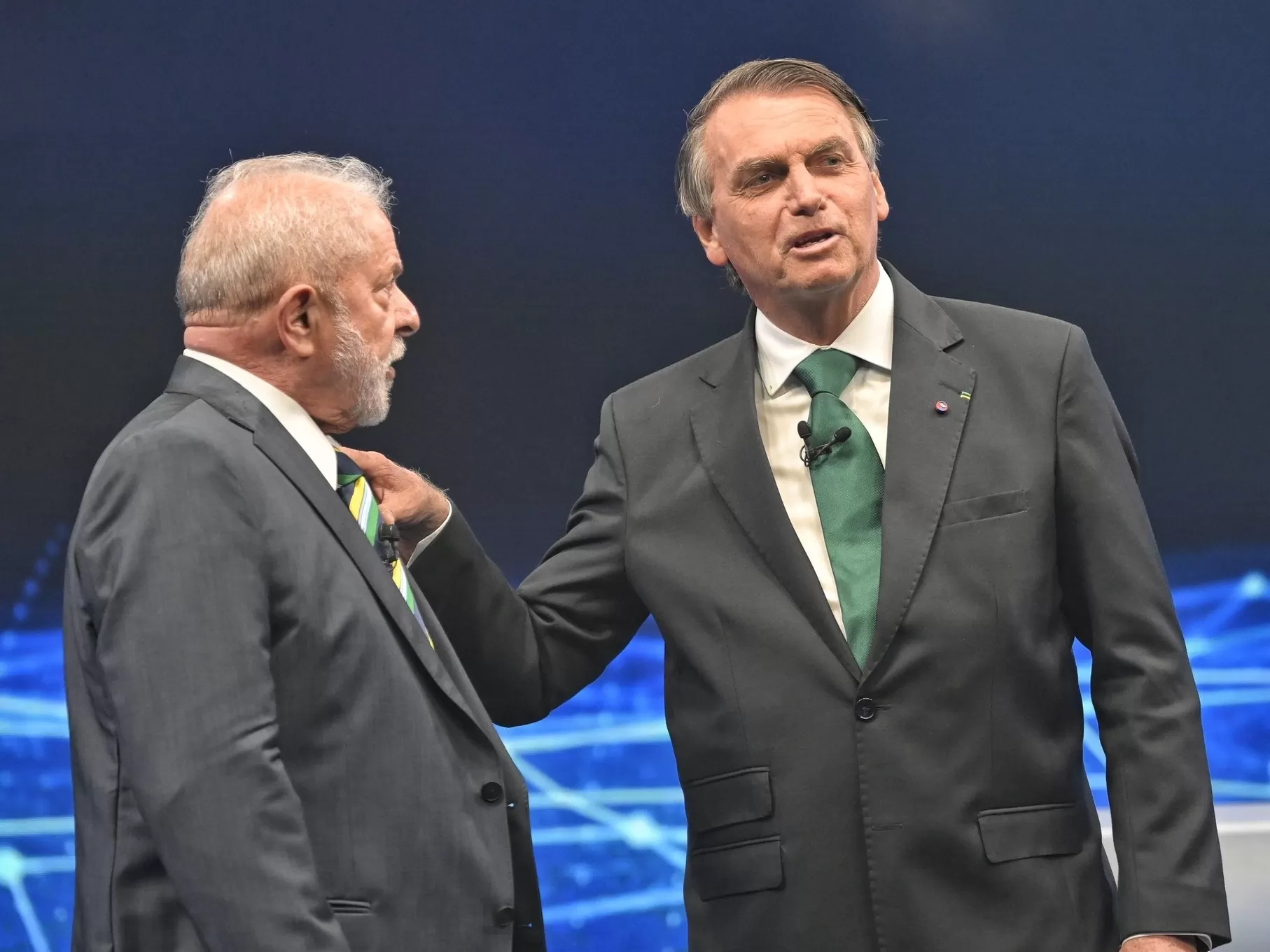 Lula e Bolsonaro, lado ao lado, durante o debate na Band, ambos com terno preto e camisa branca; foto ilustra a matéria sobre os gastos com o cartão corporativo de ambos.